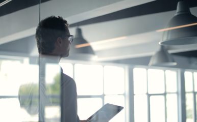 Man with tablet performing risk evaluation for a property in light-filled room.